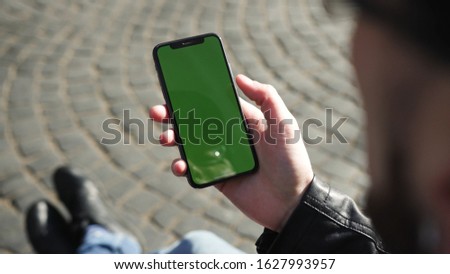 Lviv, Ukraine - May 19, 2018: In city center man hands holding use touch phone with horizontal green screen street background sunset busy finger touch message cellphone display girl slow motion