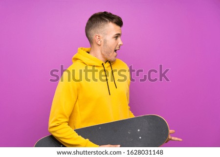 Young blonde man holding a skate with surprise facial expression