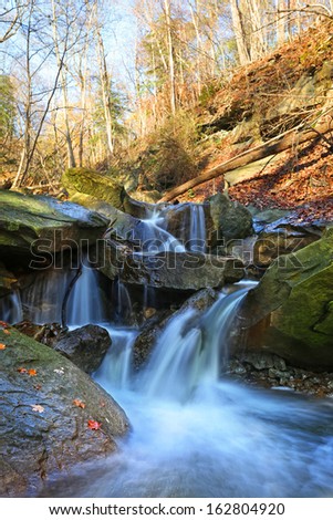water cascades on a mountain river with fallen autumn leaves 