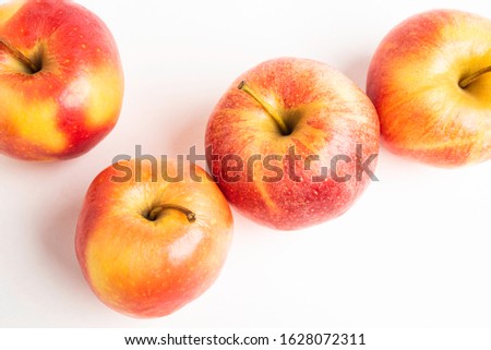 A group of four fresh red apples set on a plain neutral background.