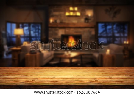 Rustic table top with blurred fireplace in luxurious home interior. Table background with empty space for products and decorations.