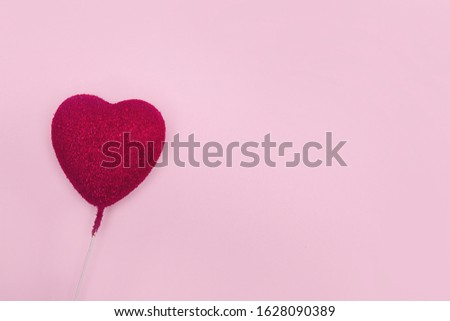 Dark pink heart on a stick on a gently pink background. Free space for text. Background for Valentine's day in pink colors.