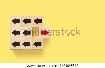 Wooden block with red arrow facing the opposite direction black arrows, Unique, think different, individual and standing out from the crowd concept
