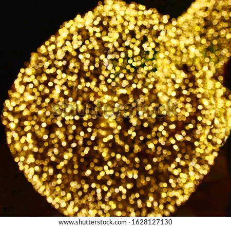 The beautifully glittering bokeh is shaped like a large golden fire ball on a black background with soft light effect