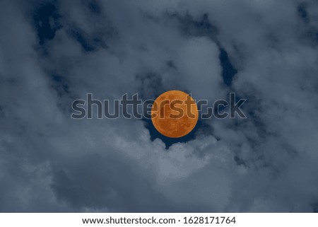 Full orange moon with blurred cloud on night sky.