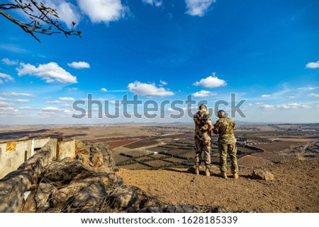 Two military personnel surveying the landscape