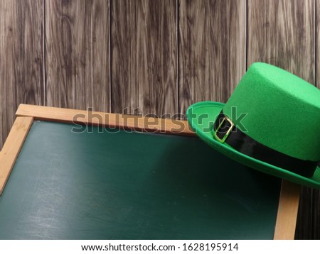 green hat on blackboard and wooden background with copy space, st. patricks day concept