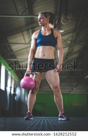 Female fitness model doing kettle bell exercises in a gym