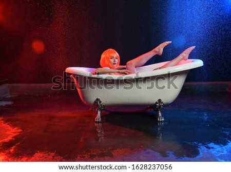beautiful girl with orange hair posing in a white bath on a red-blue background