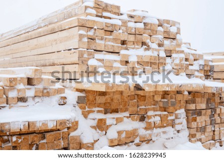Building materials in the winter, wooden planks and bars for sale on the construction of a house.