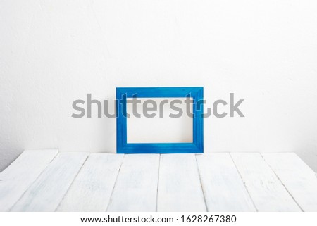 one empty blue picture frame on white wooden table