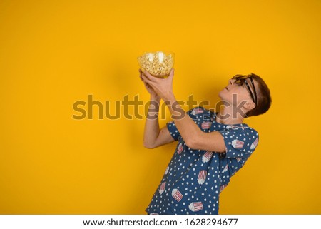 free advertising place a man in a t-shirt with 3D glasses looks at a free popcorn place on a yellow background