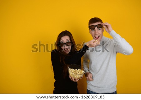 young couple together at the cinema in 3D glasses on a yellow background