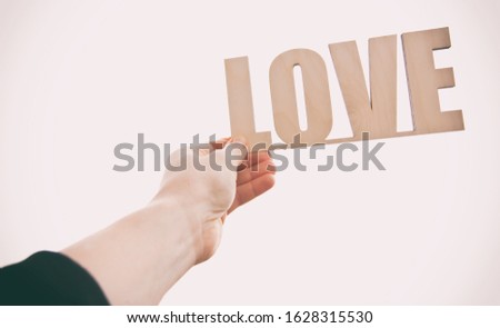 The wooden word LOVE in the woman's hand against the sunset
