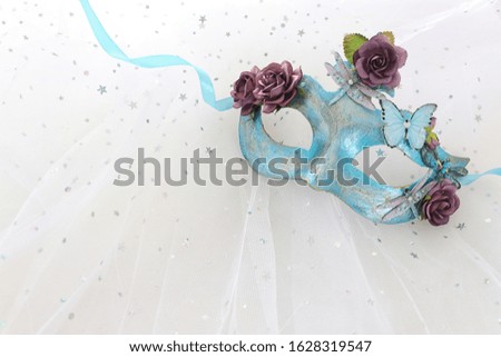 Photo of elegant and delicate blue Venetian mask over white chiffon background