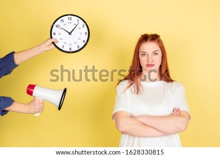 Time out. Caucasian young woman's portrait on yellow studio background, too much tasks. How to manage time right. Concept of office working, business, finance, freelance, self management, planning.