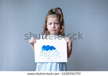 
sad little girl holding a cloud drawing