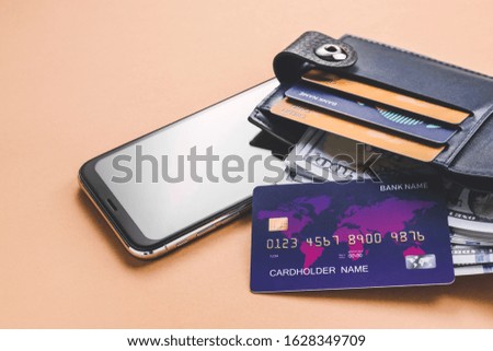 Wallet with credit cards, money and mobile phone on color background