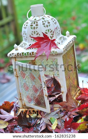 old lantern with maple leaves on a deck 