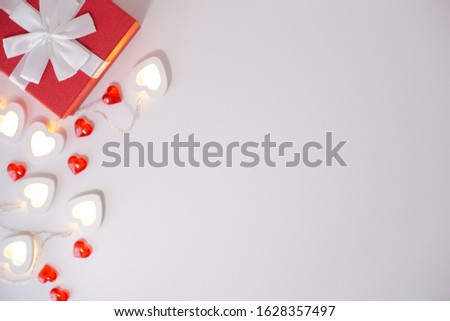 Red gift box , bright white heart-shaped garlands on a white background.