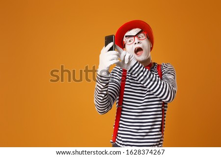 Mime man in white gloves and red hat takes selfie on orange background