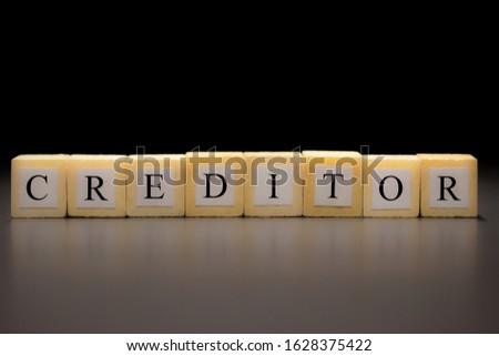 The word CREDITOR written on wooden cubes isolated on a black background...