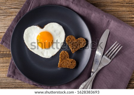 Valentines day breakfast with heart shaped fried eggs served on grey plate and napkin. flat lay, top view