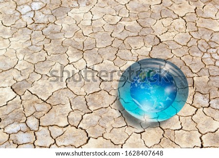 The glass globe (the world) in the form of drops on dry soil - Global warming and ecology concept "Elements of this image furnished by NASA "