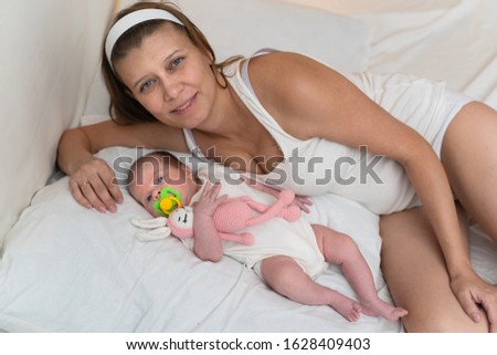 Mother with a newborn baby in the bedroom on the bed at home