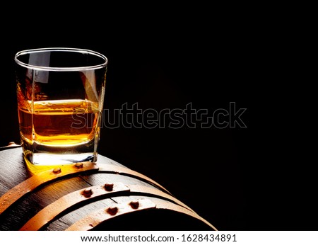 Whiskey sample, whiskey glass stands on a whiskey barrel Royalty-Free Stock Photo #1628434891