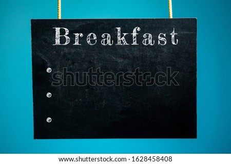 Chalk board hanging with the inscription "breakfast" and dots mocap on a blue background. copy space
