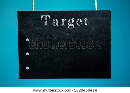 Chalk board hanging with the word "target" and dots mocap on a blue background. copy space