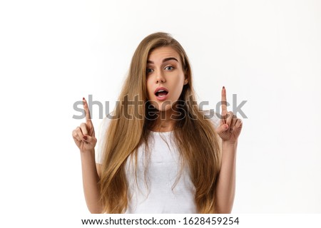 smiling young woman pointing up on white background.