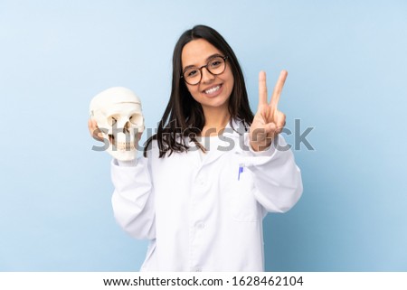 Police forensic specialist girl over isolated background smiling and showing victory sign