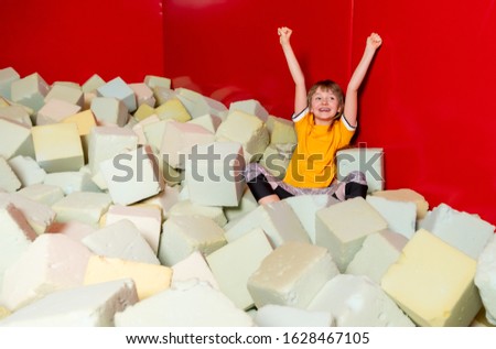 Child girl having fun in soft box pool in indoor playground center