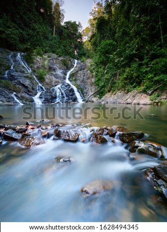 Scenery of waterfall known as "Lata Meraung" (translate to screaming rapid) with clear water surrounded by green rain forest. Long exposure shot to show the movement of water.
