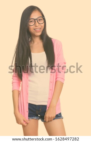 Studio shot of young happy Asian teenage girl smiling