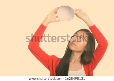 Studio shot of young Asian teenage girl showing empty coffee cup