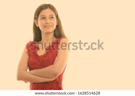 Studio shot of happy young beautiful woman smiling and thinking with arms crossed