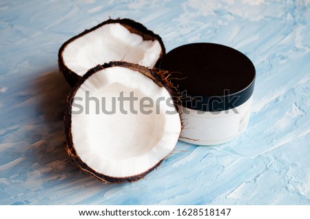
Coconut skin cream and two halves of coconut on a blue texture background