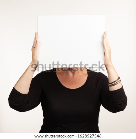 Woman holding up a blank white sign with room for your copy. Advertisement concept.