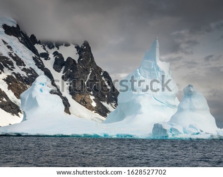 towers of giant iceberg with view to rocks in bar