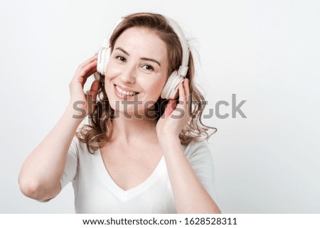 Happy woman in the wireless earphones looking at the camera