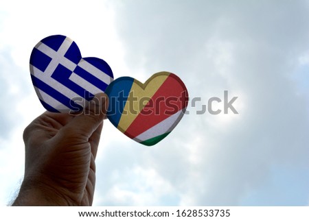 Hand holds a heart Shape Greece and Seychelles flag, love between two countries