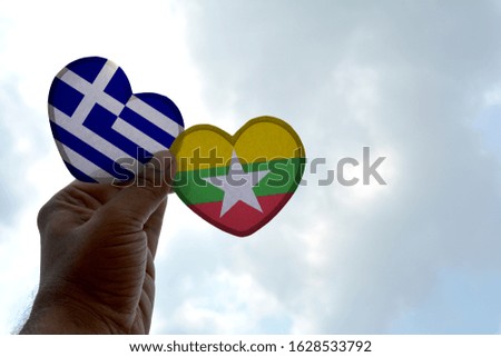 Hand holds a heart Shape Greece and Myanmar flag, love between two countries