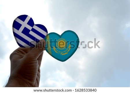 Hand holds a heart Shape Greece and Kazakhstan flag, love between two countries