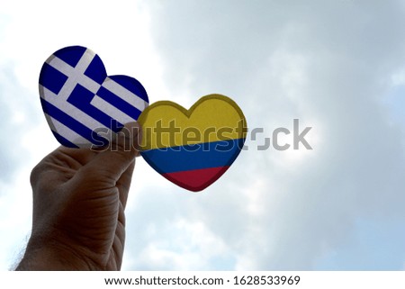 Hand holds a heart Shape Greece and Colombia flag, love between two countries