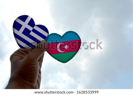 Hand holds a heart Shape Greece and Azerbaijan flag, love between two countries