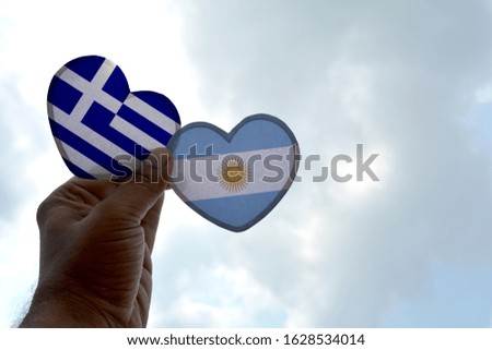 Hand holds a heart Shape Greece and Argentina flag, love between two countries