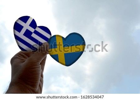 Hand holds a heart Shape Greece and Sweden flag, love between two countries